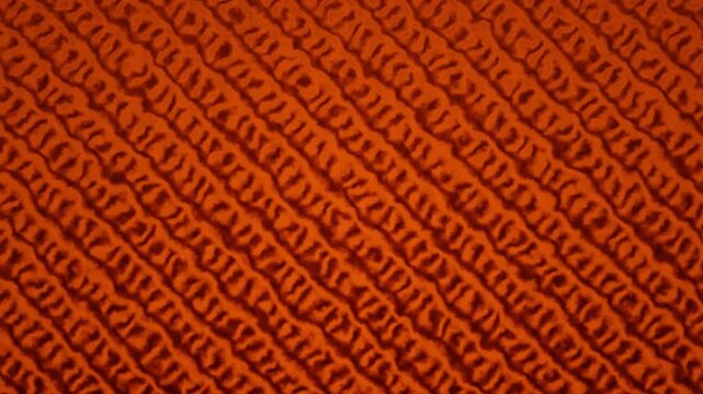 Abstract texture of a knitted wool background pattern showing loop details in orange and red