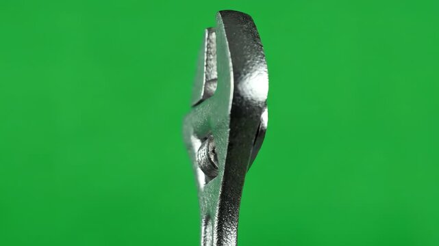 Professional unbranded steel adjustable wrench rotating slowly against a bright chroma key green screen background