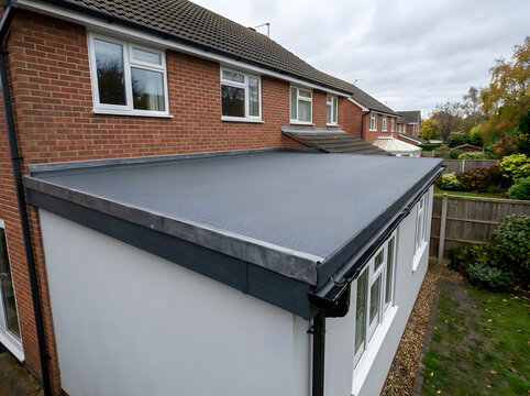 modern grey flat roof extension | residential flat roofing installation with lead flashing | black guttering and fascia on home extension | durable waterproof flat roof system