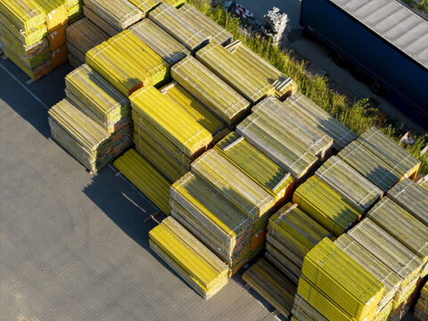 Aerial view of stacked yellow construction formwork panels in a storage yard with a truck parked nearby in Krakow, Lesser Poland Voivode, Poland.