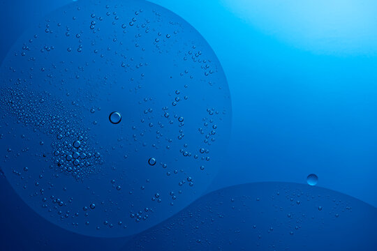 Blue liquid with oil drops creating abstract bubbles
