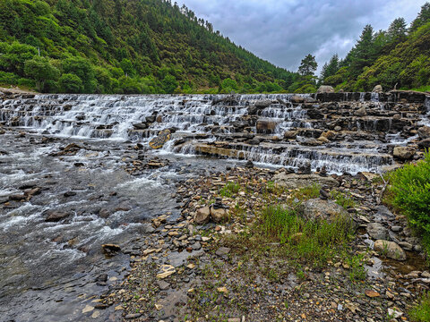 Mountain stream with cascading waterfall and green forest in China