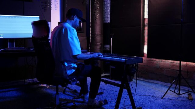 Music Producer Playing MIDI Keyboard In Modern Recording Studio
