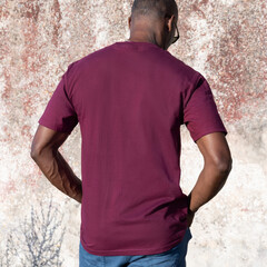 Blank dark red t-shirt mockup on smiling black man outdoors, back view with copy space