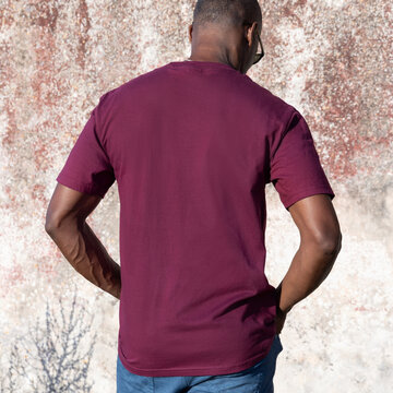 Blank dark red t-shirt mockup on smiling black man outdoors, back view with copy space