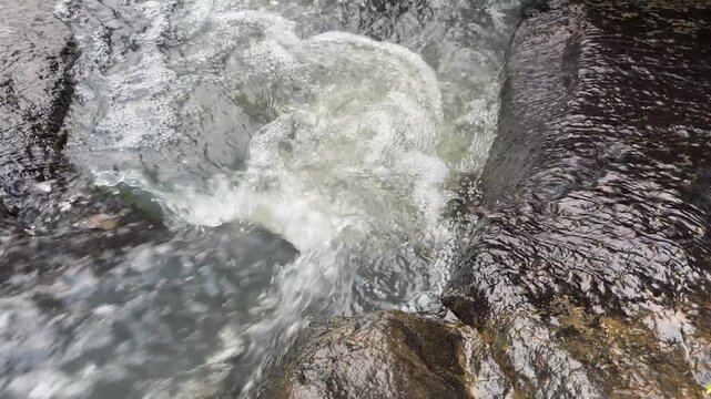 Swirling River Water Current Over Dark Rocks