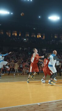 Basketball Players Battling for Position Under the Hoop in a Packed Arena