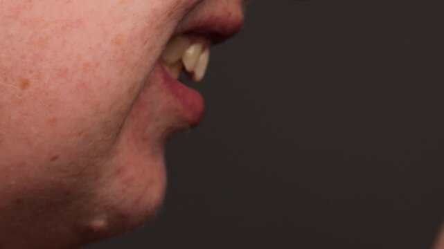 side view of open mouth showing teeth alignment, macro profile shot of jaw and lips during bite examination, dental occlusion detail on dark background with copy space, concept of orthodontics, dental