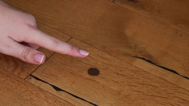 hand reaching for last small coin on wooden floor, close up of finger touching copper penny as symbol of poverty and financial crisis, faceless shot with warm wood texture, concept of banking, debt co