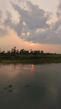 Serene sunset over calm river reflecting golden sky and silhouetted trees tranquil natural