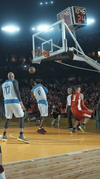 Basketball Player Dunking the Ball Over a Defender in a Packed Arena