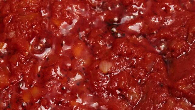 tomato sauce with onion simmering in olive oil close up, chopped vegetables stewing in pan with black pepper, thick homemade sofrito cooking process, concept of italian cuisine, restaurant menu, home 