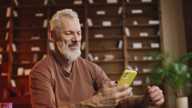 Stylish mature man choosing a new fitness app after a home workout, gadgets