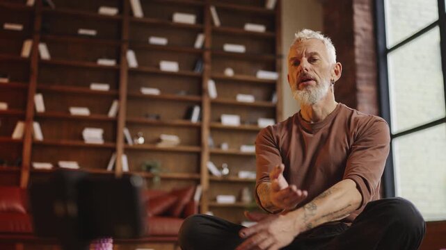 Handsome middle-aged man recording a video for his yoga blog while exercising