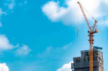 Tower crane operating beside a high rise building construction project. Modern civil engineering, infrastructure development, commercial real estate, urban expansion and construction industry concept. © Fahroni
