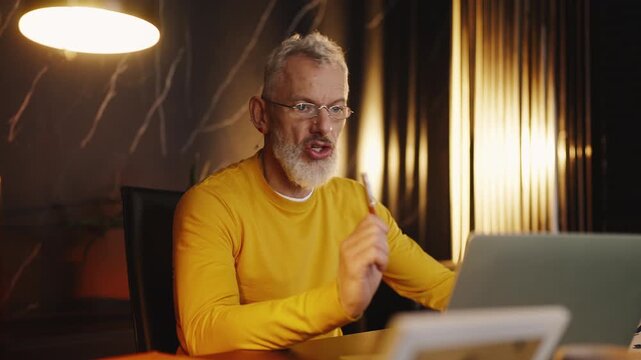Stylish mature IT company executive having a video call on a laptop in office