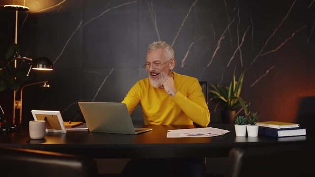 Mature company CEO reading good news in an email and celebrating success