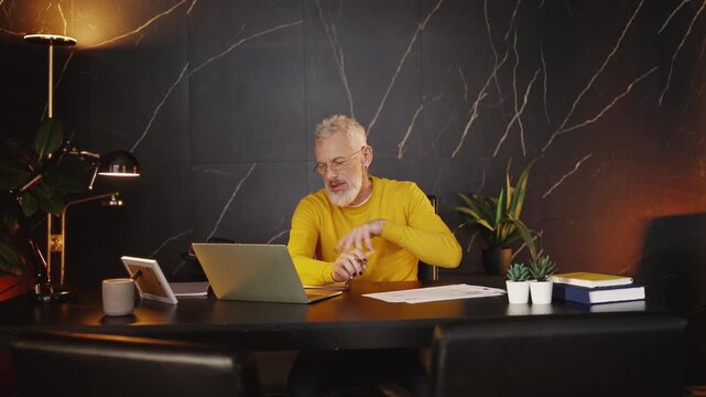 Middle-aged businessman working with documents and typing on a laptop in office