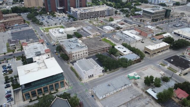 Downtown core Bowie Street intersects Houston Street near commercial parking zones. Low-rise architectural blocks border municipal thoroughfares in historic downtown San Antonio, Texas