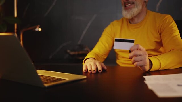 Middle-aged corporate executive using a credit card to make a payment on laptop