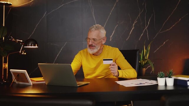 Stylish mature company CEO shopping online and entering a credit card number