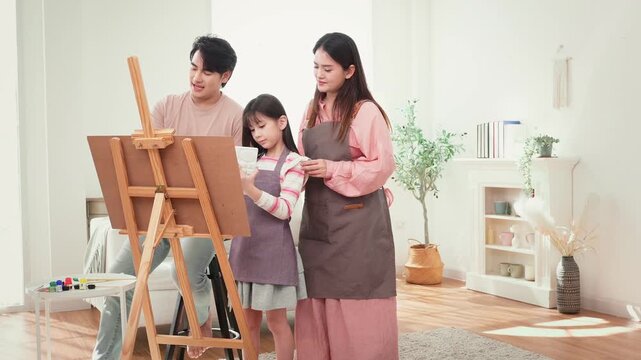 Girl Enjoys Painting With Parents at Home During a Family Activity