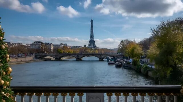 Paris, France, Europe. A vivid portrayal of Paris, France, captured from a balcony overlooking the Seine River. The Eiffel Tower stands tall against a clear blue sky with fluffy white clouds.