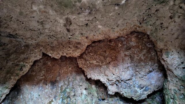 Xemxija, Malta 29.07.2026 - Heritage trail, Roman Baths, shelf like cut in the stone Dark cave walls show rough, textured surfaces. Greenish moss grows on damp, uneven stone. Light filters through nar