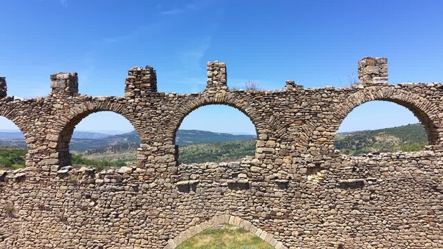 Historic Roman viaduct ruins near Morella, Valencia, Spain, featuring rows of stone arches against a blue sky with mountain landscape visible through the openings