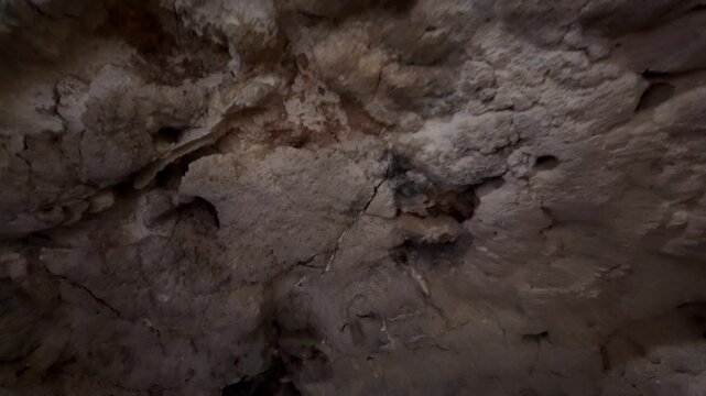 Xemxija, Malta 29.07.2026 - Heritage trail, Roman Baths, shelf like cut in the stone Dark cave walls show rough, textured surfaces. Greenish moss grows on damp, uneven stone. Light filters through nar