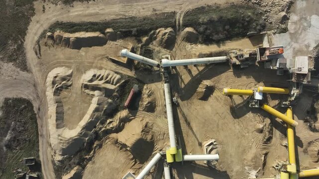 Aerial view of a sand quarry and gravel pit. Open-pit mining for construction materials with heavy machinery, conveyor belts, and processing equipment. Industrial background from above.