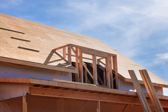 Workers are busy building new house roof, using wooden beams frames trusses roofing materials