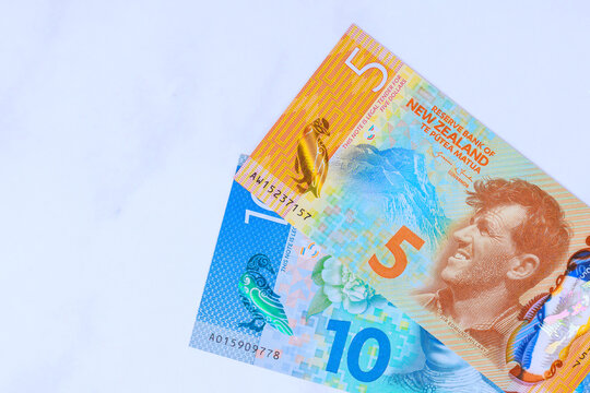 Five, ten dollar notes from New Zealand are placed on clean white surface