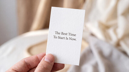 Fototapeta premium Hand holding a small white card with the inspirational quote the best time to start is now written on it