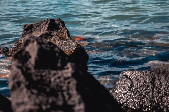 Dark volcanic rock formation in clear sea water