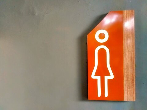 Female Toilet Direction Sign on Interior Wall with Orange and Wood Design