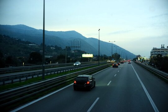 Cars driving on modern highway at dusk against scenic mountain landscape