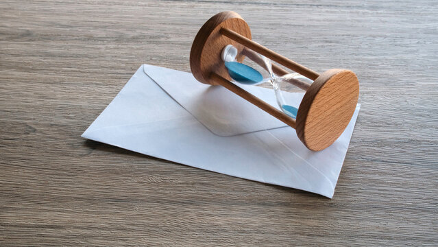 Wooden Sand Hourglass Resting on White Mail Envelope