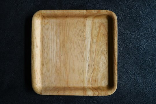 A square wooden plate with smoothly rounded corners. Minimalist kitchenware products like this are typically crafted from high quality, food grade solid wood.