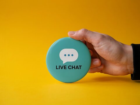 Hand holding live chat button against bright yellow background