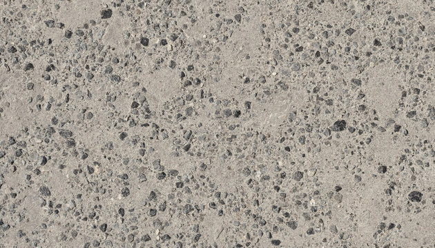 A close up view of exposed aggregate concrete surface with small dark pebbles embedded in a light gray cement matrix for a rough texture