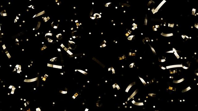 Shiny yellow party tinsel drops slowly down a dark setting