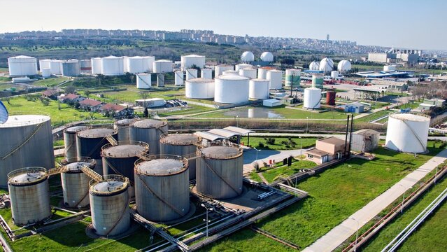 Aerial view of the Ambarli oil terminal with numerous large white storage tanks, industrial infrastructure, and pipelines set against a backdrop of urban development in Avcilar, Istanbul, Turkey.
