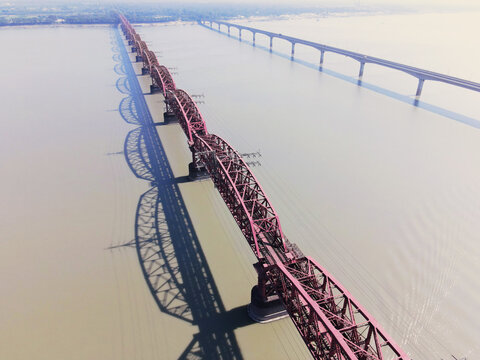 Aerial view of the historic Hardinge Bridge spanning the Padma River with its intricate steel truss structure casting long shadows on the water in Pabna, Rajshahi Division, Bangladesh.