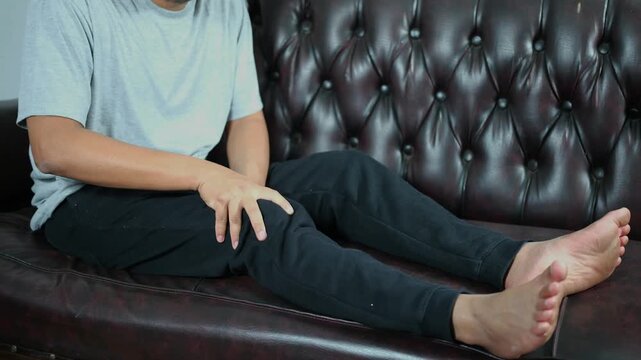 A young man massages his knee due to knee pain and muscle aches caused by Runner's Knee or Patellofemoral Pain Syndrome, osteoarthritis, arthritis, rheumatism, and Patellar Tendinitis. Medical concept