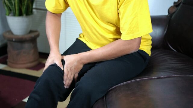 A young man massages his knee due to knee pain and muscle aches caused by Runner's Knee or Patellofemoral Pain Syndrome, osteoarthritis, arthritis, rheumatism, and Patellar Tendinitis. Medical concept