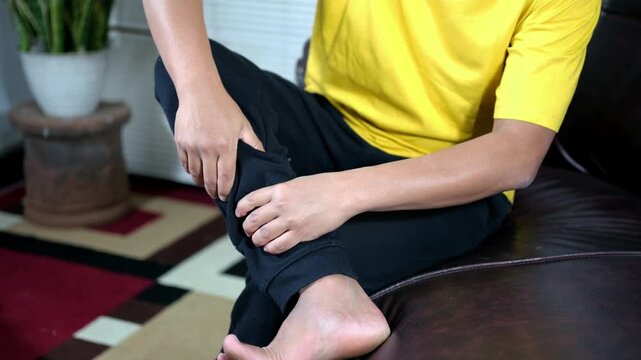A man massaging his calves and shins on a bed. Calf cramps, shin injuries, stiff muscles. Health care
