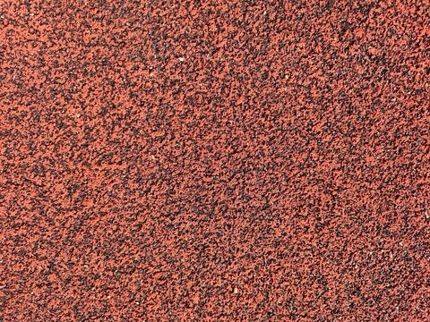 Full frame texture of a red rubber running track surface at an athletic stadium