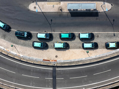 Aerial view of a taxi rank with several turquoise and black taxis parked in a row along a curved road in Lisbon, Lisbon, Portugal.