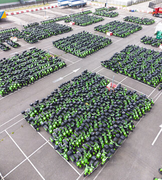 Aerial view of a large outdoor storage lot filled with rows of green electric scooters parked in an organized grid pattern in Middenmeer, North Holland, Netherlands.